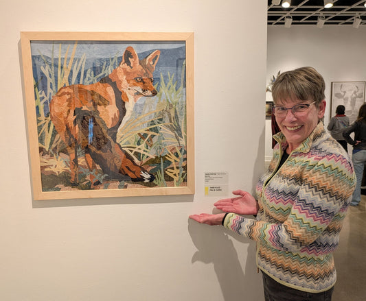 Natalija Walbridge standing next to her Red Fox fabric collage at the opening reception for the Arts North International show in Hopkins, MN